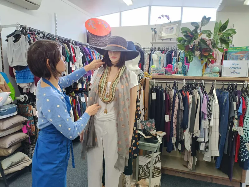 A volunteer dressing a model at the Charity Boutique store