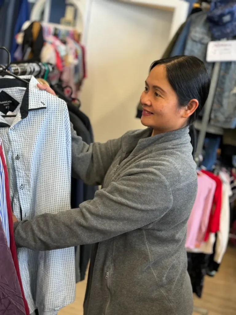 A ME Respite volunteer sorting clothing in a clothes rack