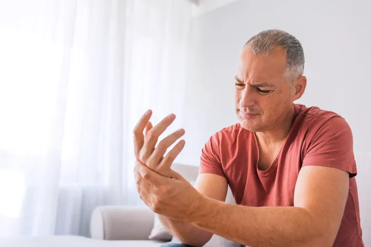 A gentleman suffering from Fibromyalgia clasping his wrist in pain