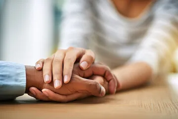 A lady and a gentleman sitting with hands clasped